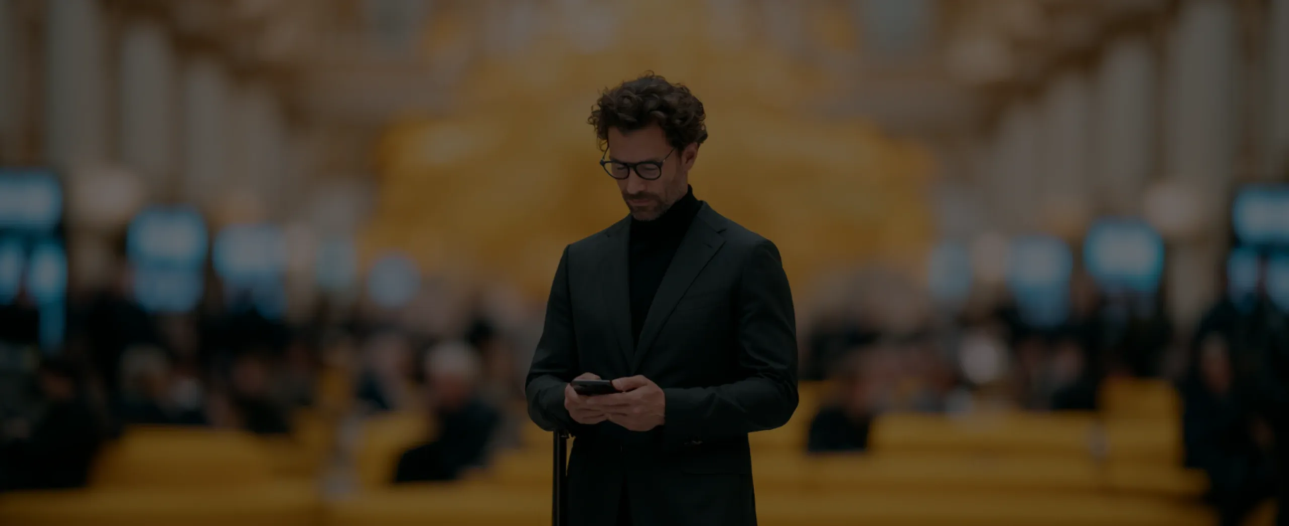 Travel and Hospitality Software Development Solutions Traveler with suitcase using a smartphone in a modern hotel lobby